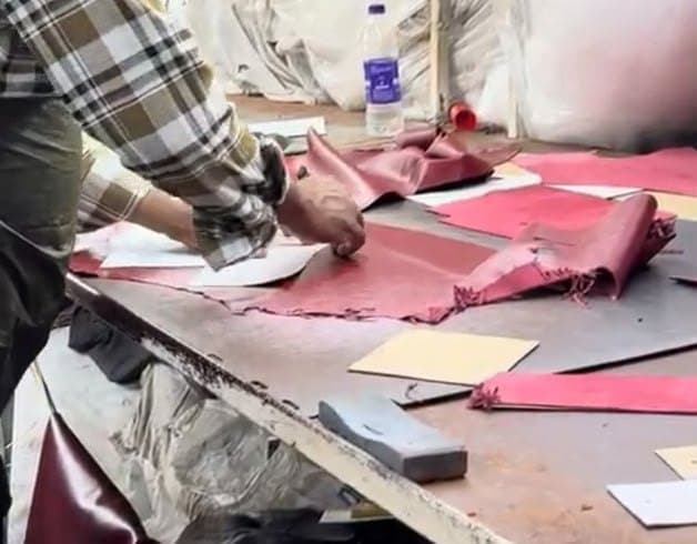 Close-up of burgundy leather pieces being cut to pattern in the CLF workshop